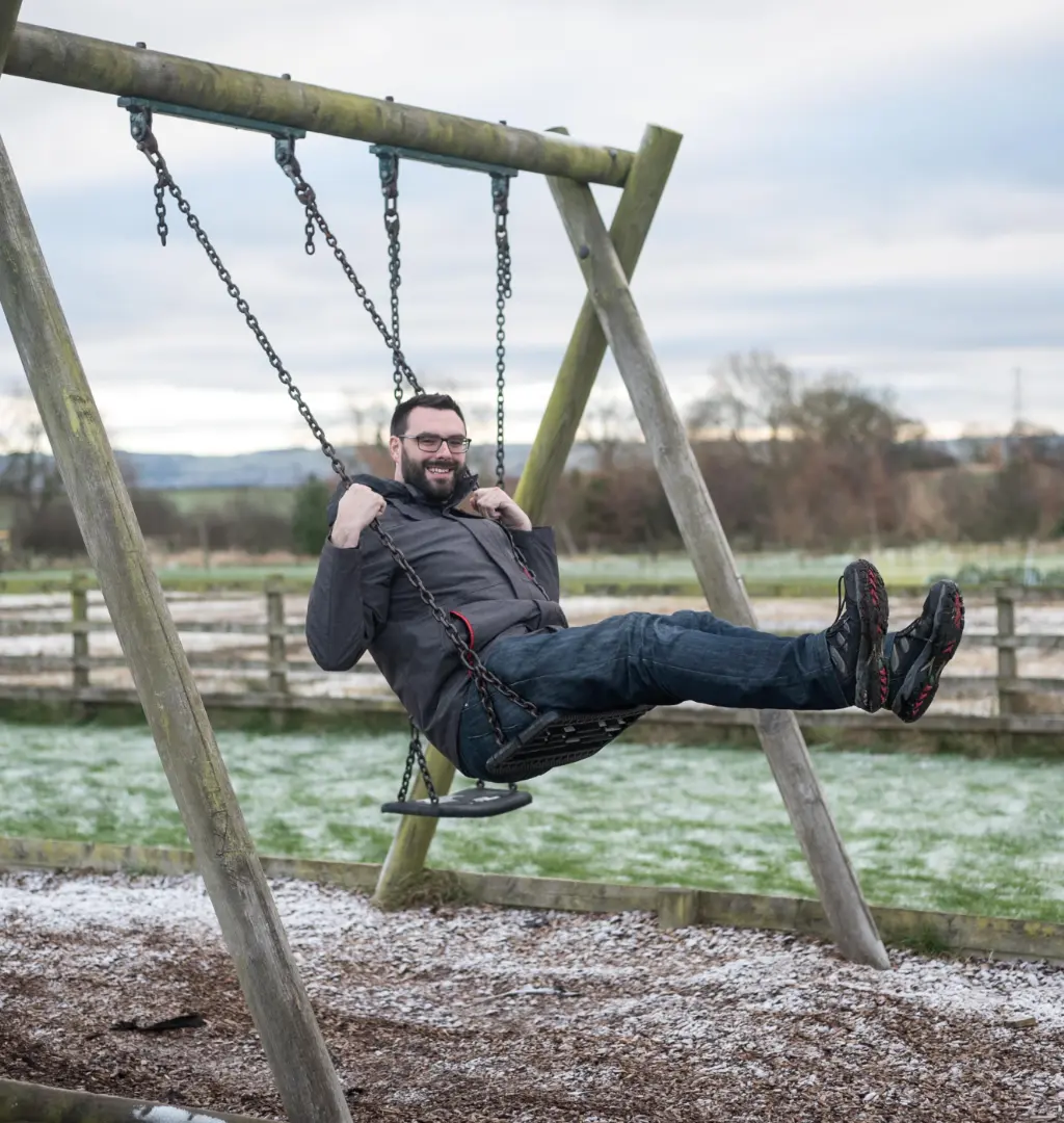 Mike sitting on swing backing onto field in Newcastle